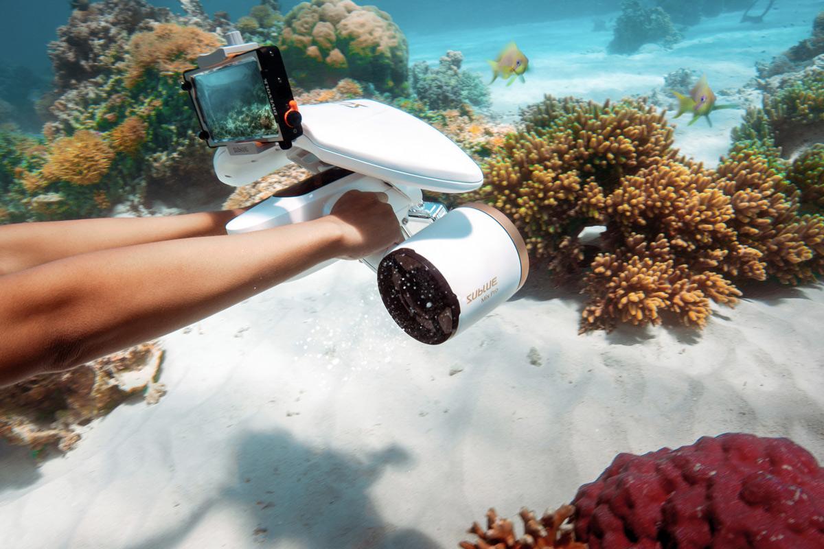 vue de coté dans une mer de coraux avec unscooter sous marin sublue