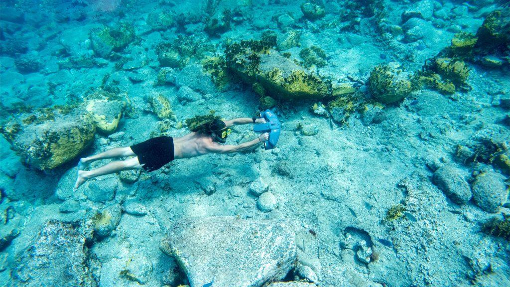Apnéiste au ras du fond rocheux avec un Sublue Navbow+