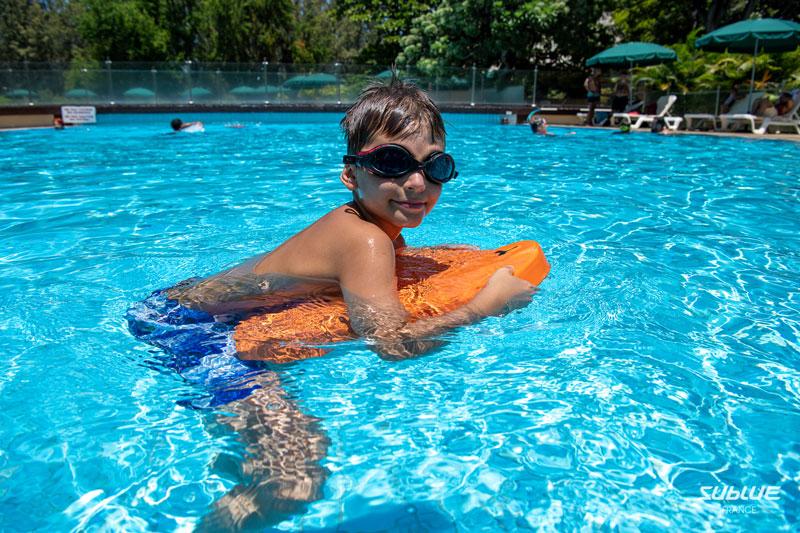 enfant en piscine avec des lunettes et une planche motorisé sublue orange