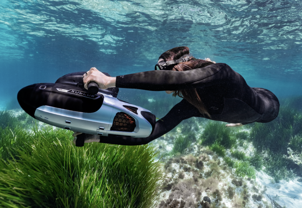 Swimmer holding a Sublue Vapor Pro above a seagrass bed