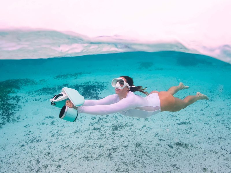 Nageuse en surface avec un scooter sous-marin Sublue WhiteShark Mix rose